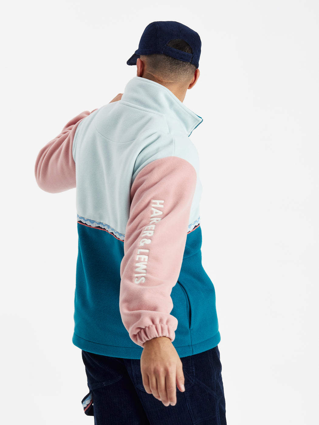 The back of the fleece jacket featuring the tape detail around the body and the half and half detail in light blue and petrol.