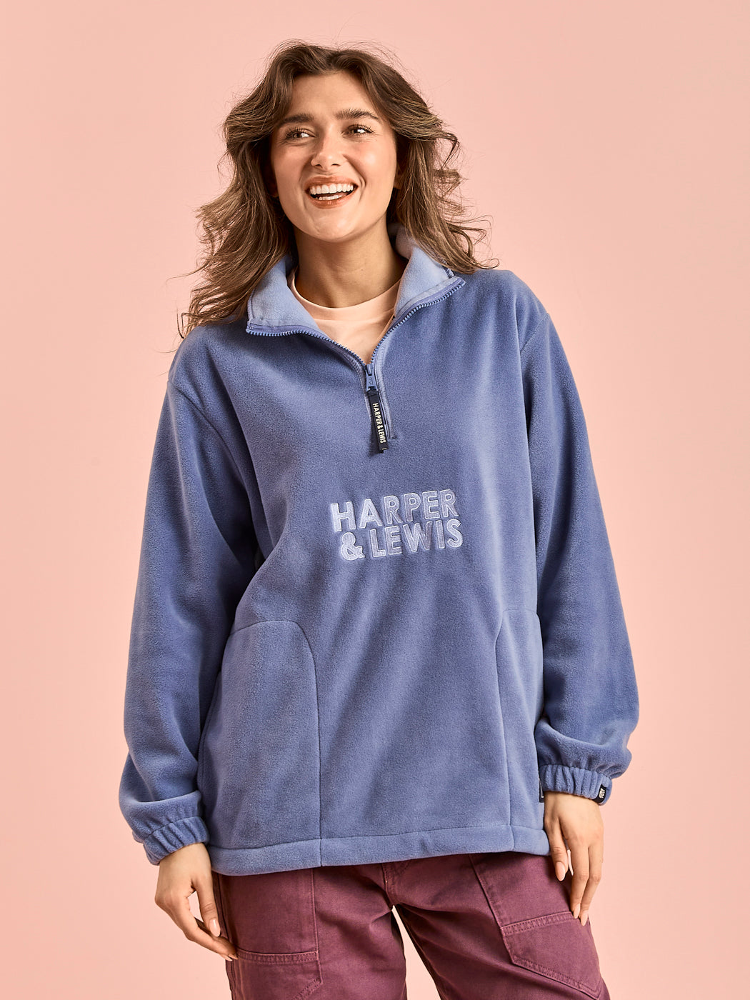 Female model wears the Airforce blue fleece which features a light Airforce blue embroidered logo on the front.