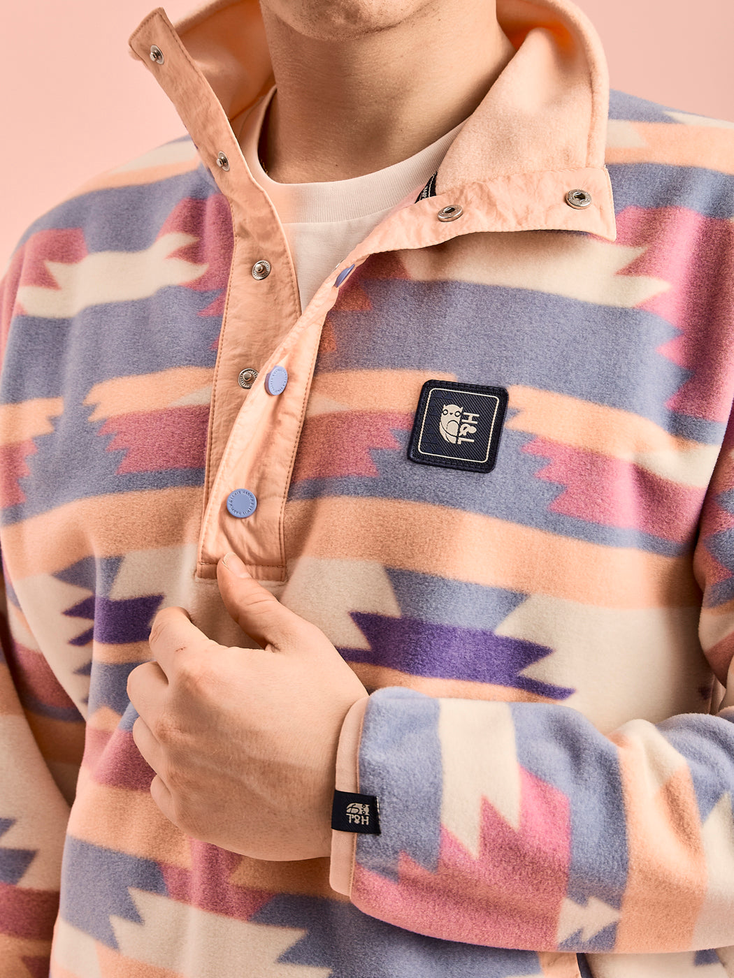 Detail shot of the Tallow fleece, which shows the branded woven badge and the cuff tab in navy