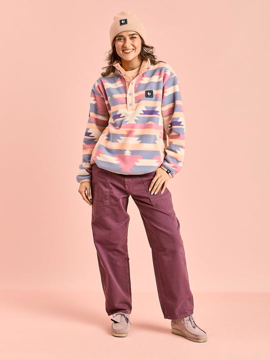 Female model wears the Tallow fleece jacket in Tribal pattern peach styled with the Asani trousers in deep mulberry