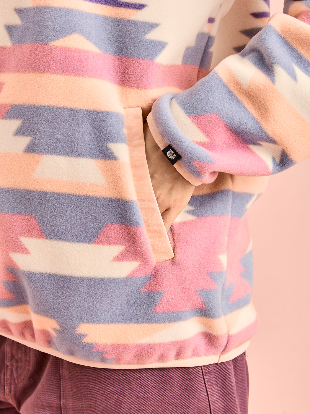 Detail shot of the light peach side entry pockets, showing the detail of the branded tab on the cuff