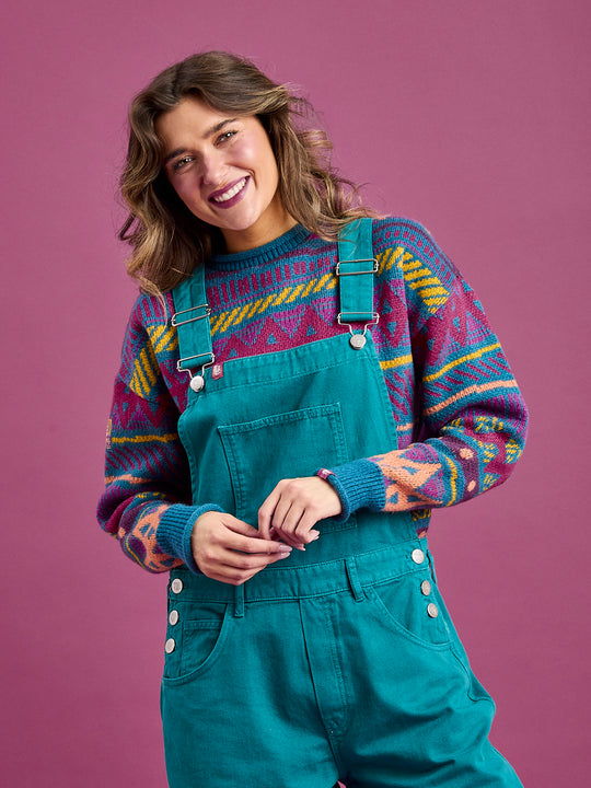 Female model wears the unisex dungarees, which features a front bib pocket