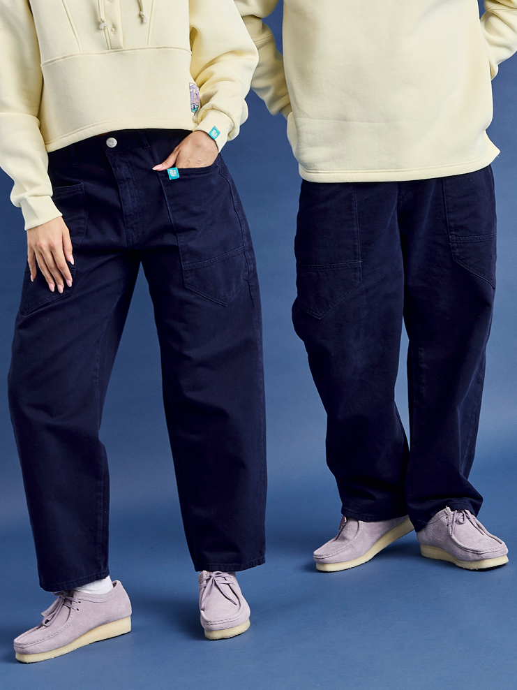 Both mondels wearing the relax fit Asani trousers in navy blue, featuring two wrap around fron pockets